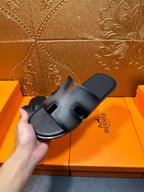 Dark blue leather slide sandals with HERMES logo on strap and open toe.