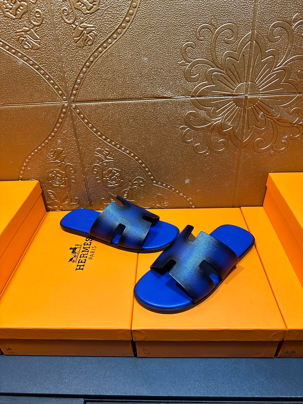 Blue textured slide sandals with black cutout design and Hermes logo on side