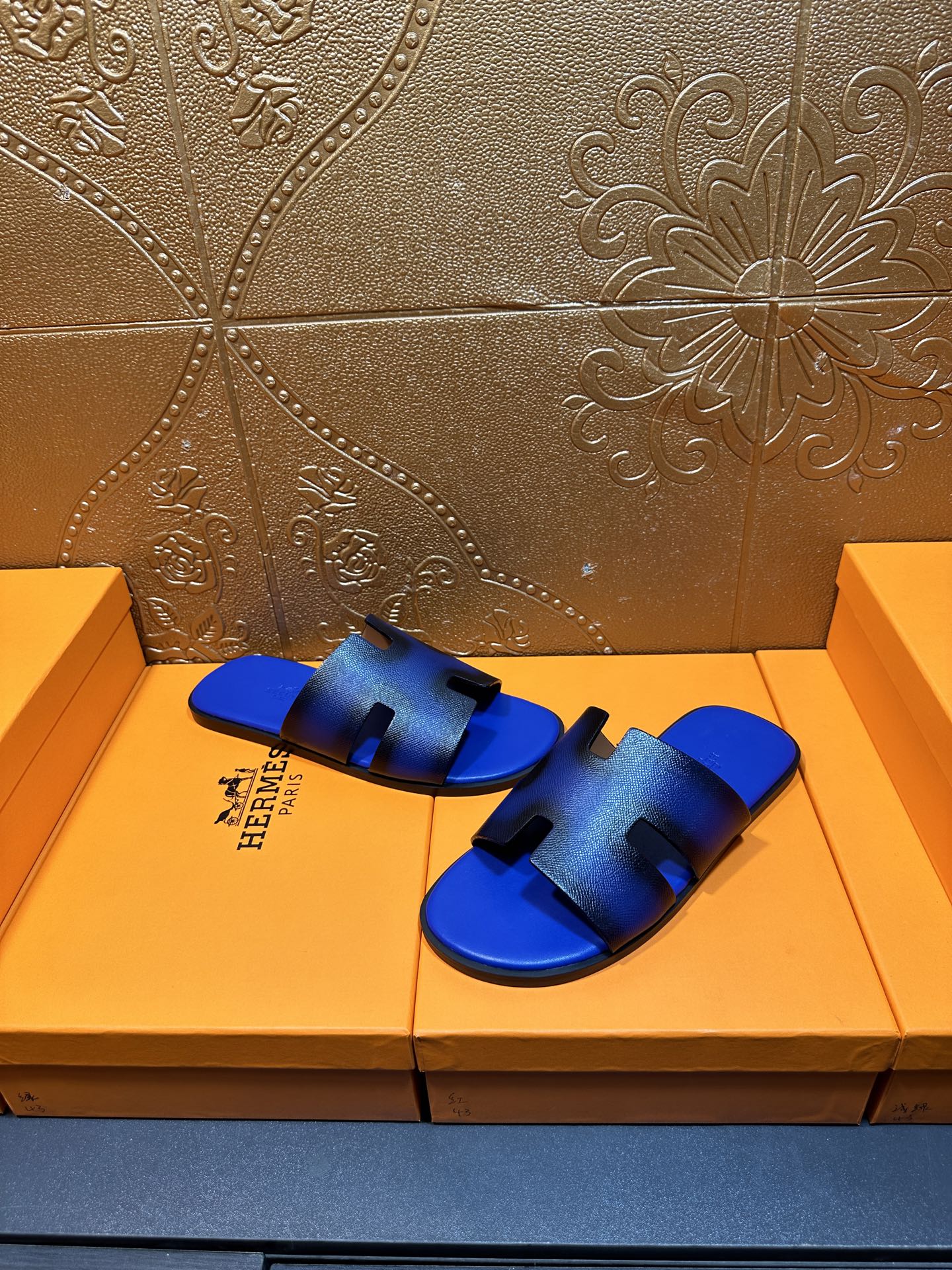Blue textured slide sandals with black cutout design and Hermes logo on side