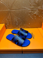 Blue textured slide sandals with black cutout bands, Hermes logo visible on strap