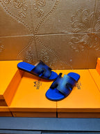 Blue textured slide sandals with black cutout straps, Hermes branding on side