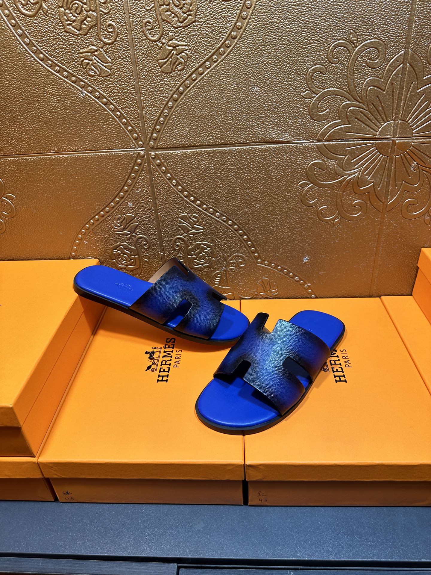Blue textured slide sandals with black cutout straps, Hermes branding on side