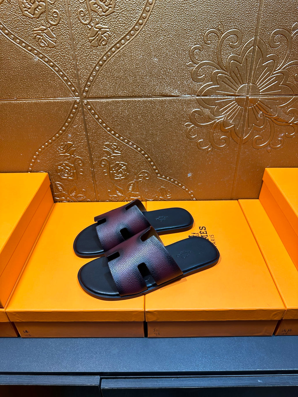 Hermes slide sandals, pair on display with H cutout straps, dark textured leather