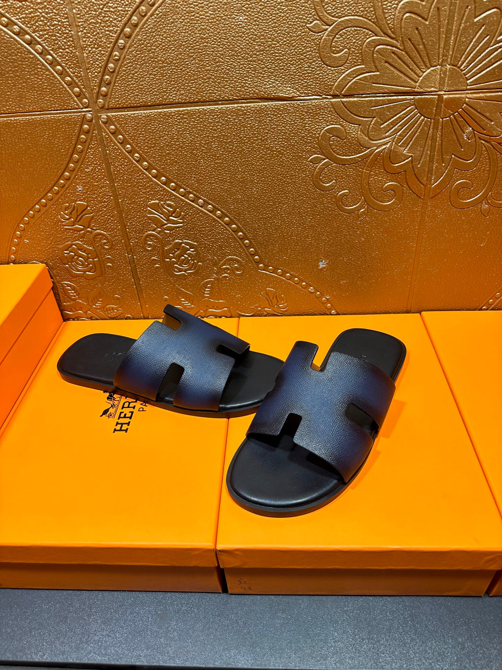 Hermes slide sandals, dark blue leather slides with H-shaped strap detail.