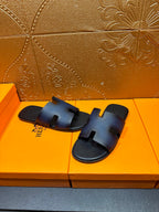 Hermes slide sandals, dark blue leather slides with H-shaped strap detail.