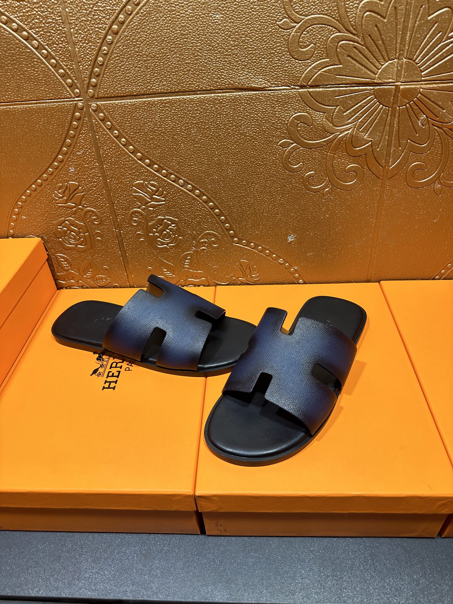 Hermes slide sandals, dark blue leather slides with H-shaped strap detail.