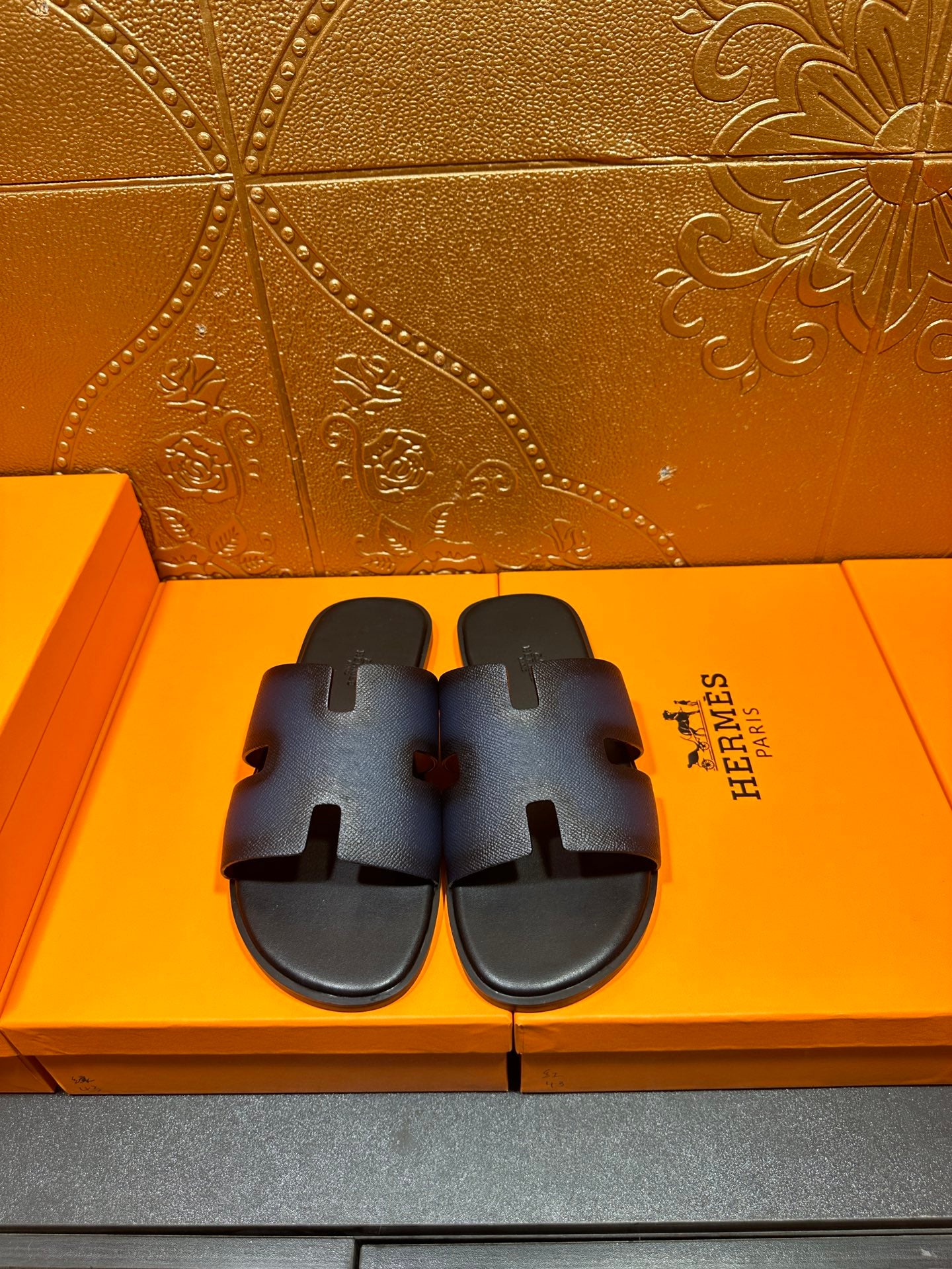 Hermes slide sandals, dark blue leather with cutout H strap and black footbed.