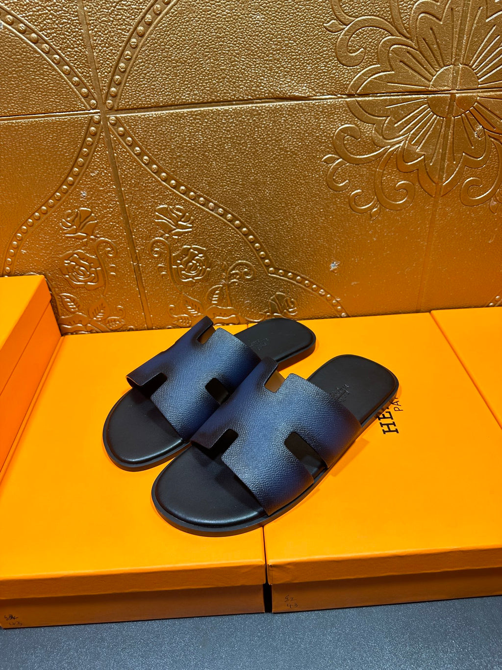 Hermes slide sandals in dark blue leather with H-shaped cutout straps.