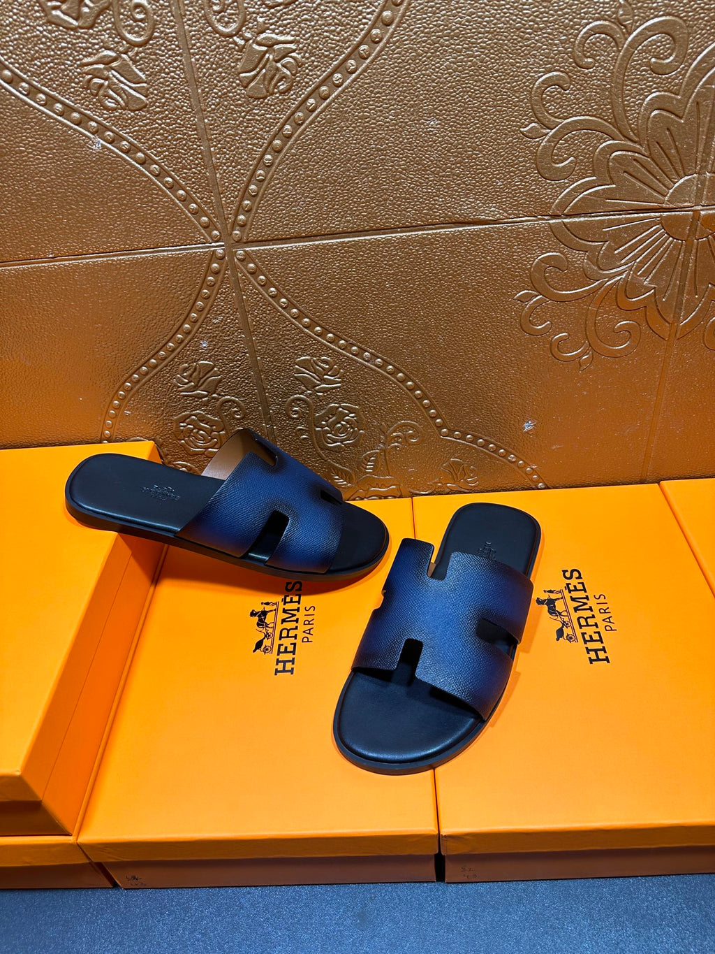 Hermes slide sandals, dark blue leather with H cutout and black molded footbed.