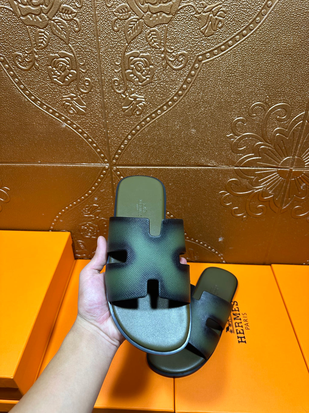 Hermes sandals close-up on hand, blue-green slide with cross strap cutouts