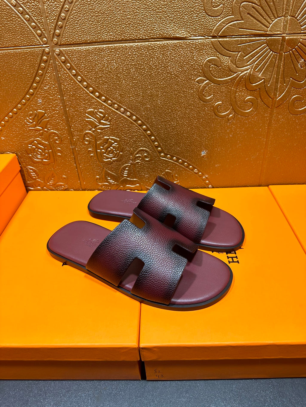 Slide sandals shown from side angle, dark purple leather straps with H buckle