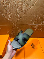 Hermes sandals held in hand, blue-green slide with cross straps