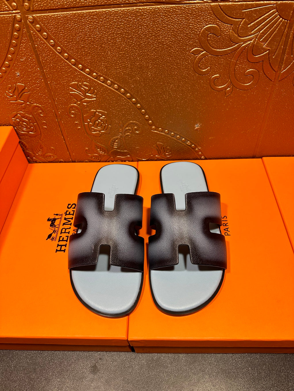 Dark navy leather slide sandals with light blue footbeds and HERMES text.
