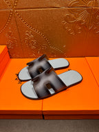 Dark navy leather slide sandals with light blue footbeds, angled view, HERMES text.