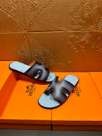Dark navy leather slide sandals with light blue footbeds, HERMES text visible on straps.