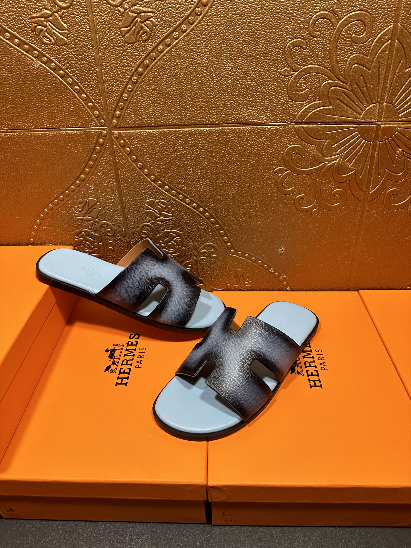 Dark navy leather slide sandals with light blue footbeds, HERMES text visible on straps.