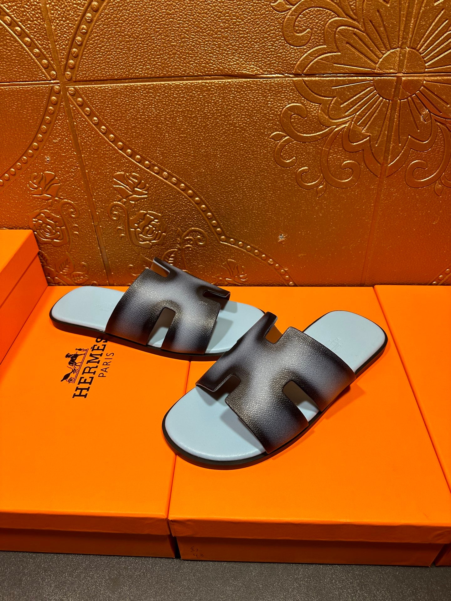 Pair of dark navy leather slide sandals with light blue footbeds and HERMES text.
