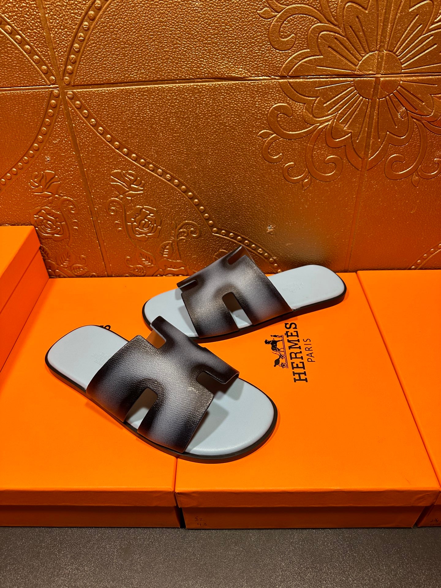 Dark navy leather slide sandals with light blue footbeds and HERMES branding on strap.