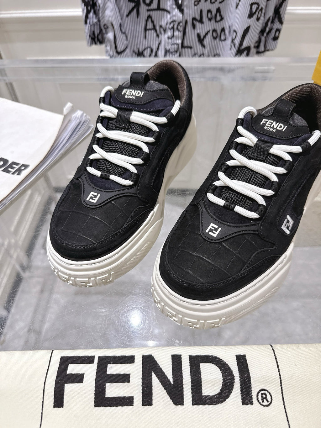 Black Fendi unisex sneakers with white laces, close-up side view of the pair