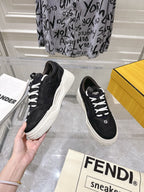 Black Fendi unisex sneakers with white laces and chunky sole, hand-held side view