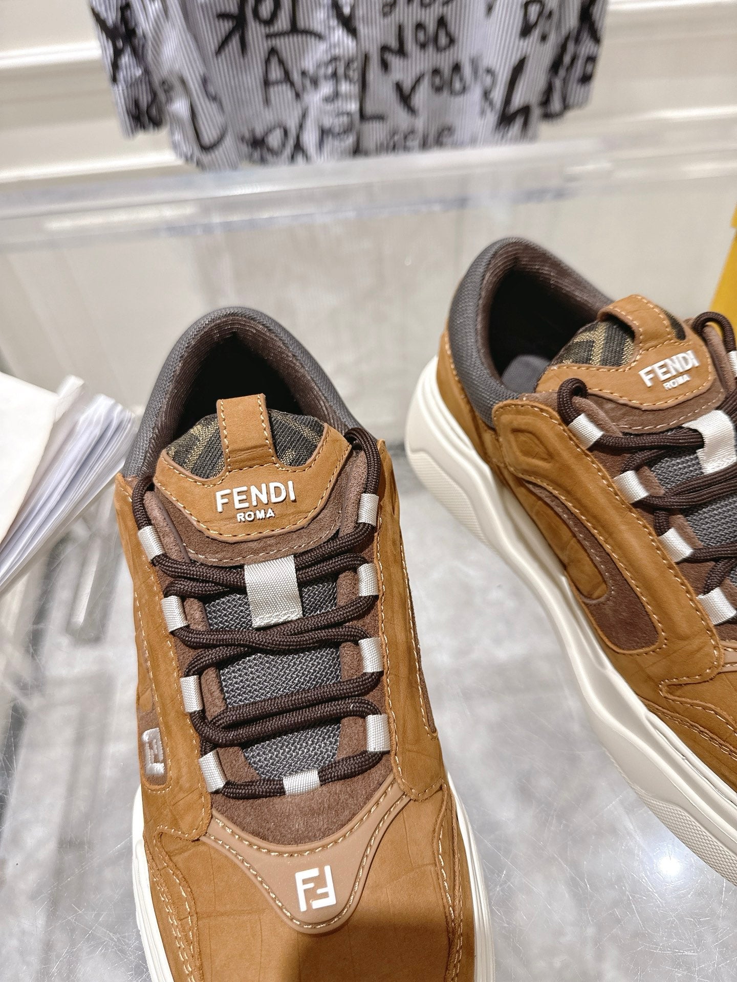 Fendi unisex sneakers close-up: tan upper, dark laces, gray logo patch