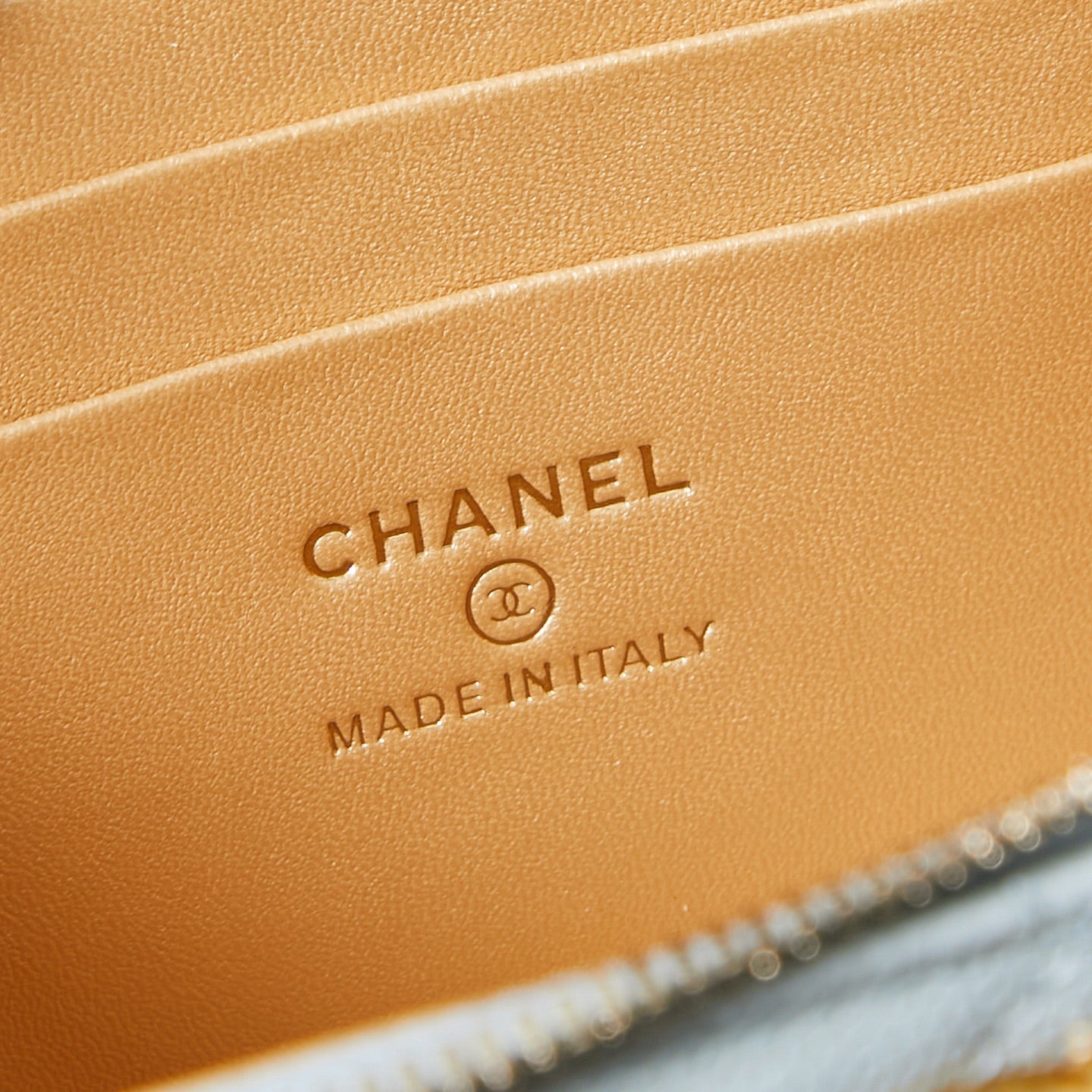 Chanel tan interior label reading CHANEL and made in Italy on quilted bag.