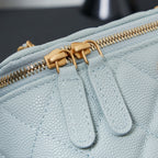 Chanel pebbled leather bag detail, light blue, with gold zipper and braided pull.