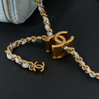 Chanel gold-tone chain strap with CC charms and clasp hardware on light blue bag.