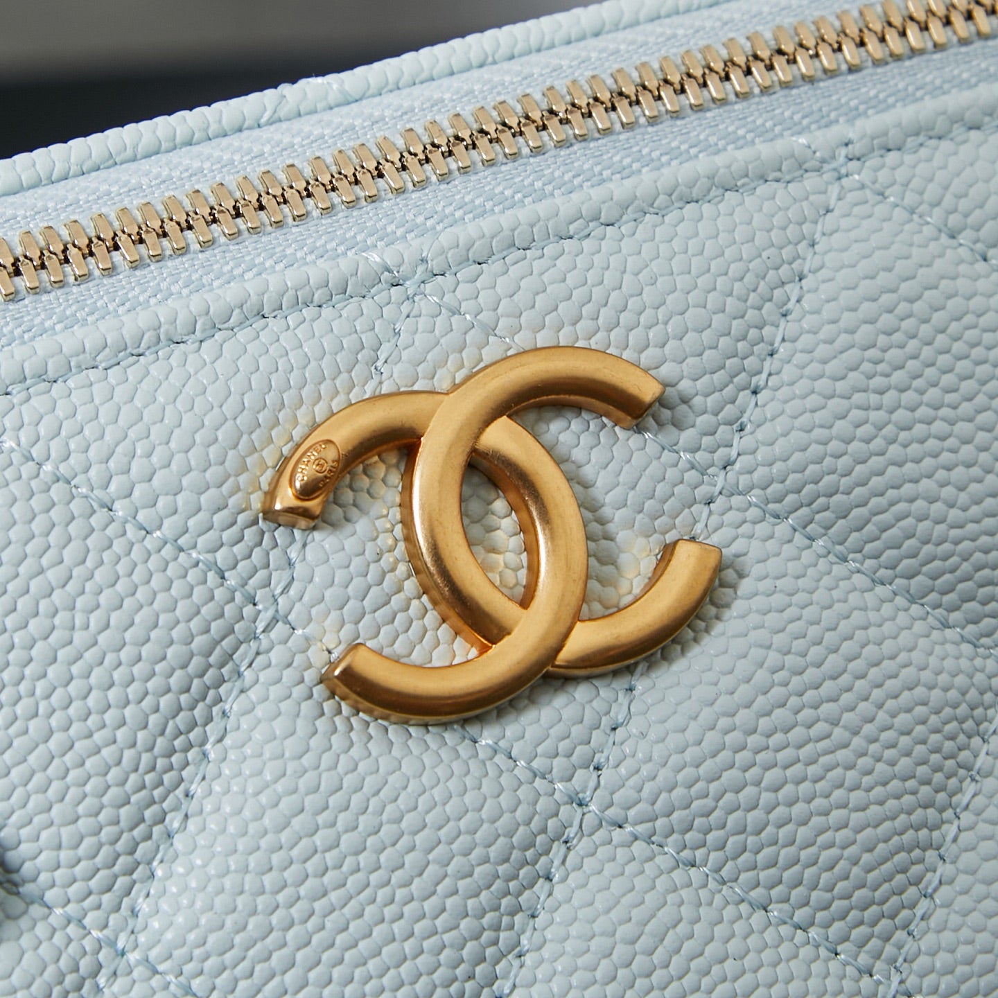 Chanel light blue bag with gold CC logo medallion on the quilted front.