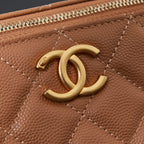 Close-up of tan quilted Chanel bag front with gold CC detail and zipper