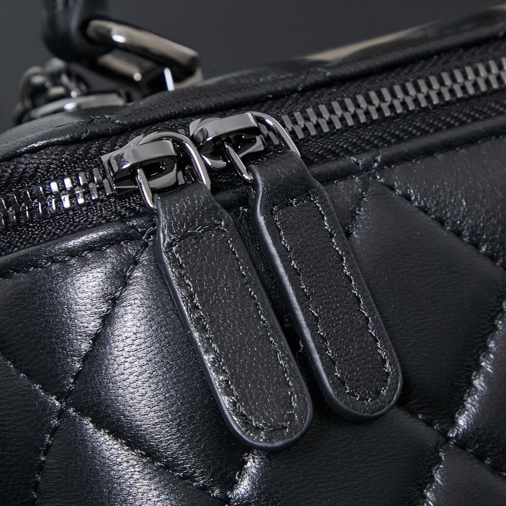 Chanel quilted leather bag close-up of zipper pulls and black leather tabs