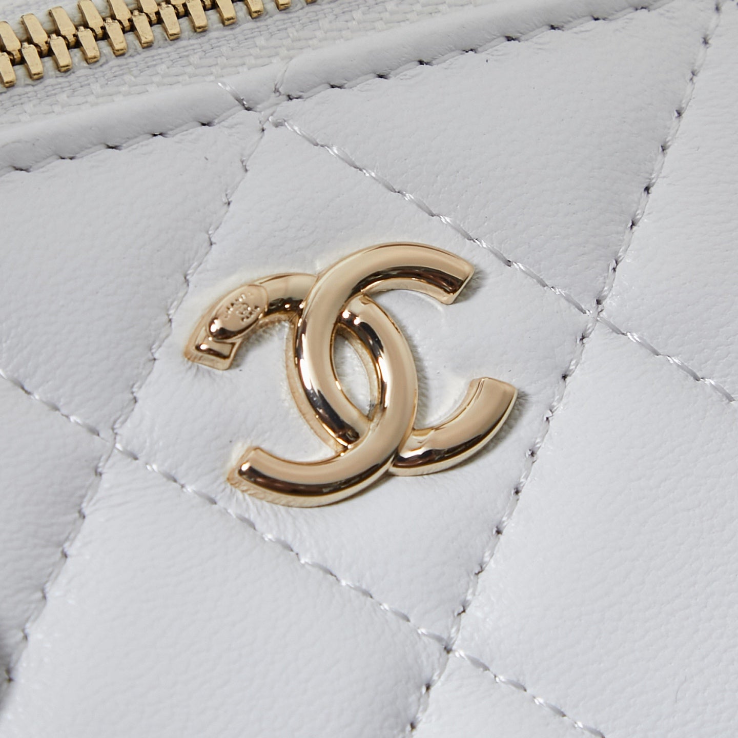 Gold Chanel CC logo on white quilted leather