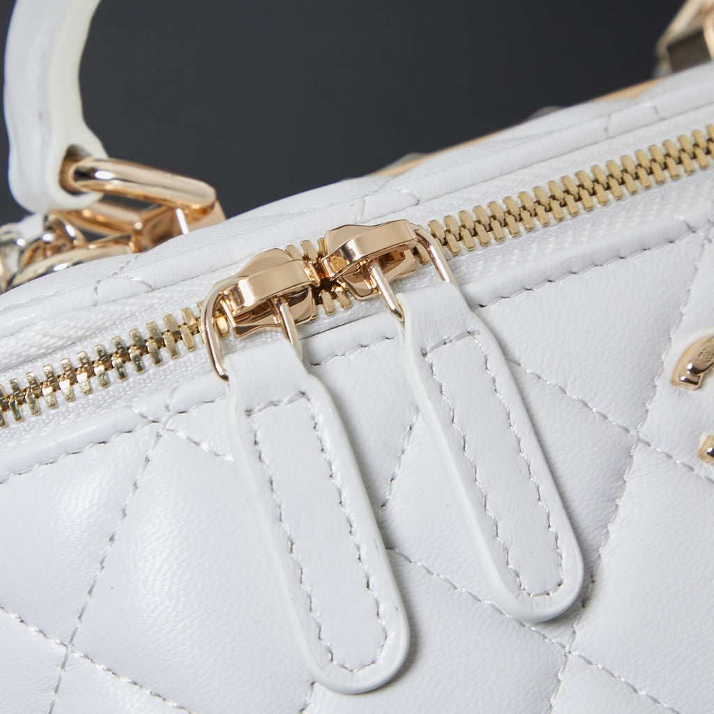 Gold zipper hardware and leather trim on white quilted bag