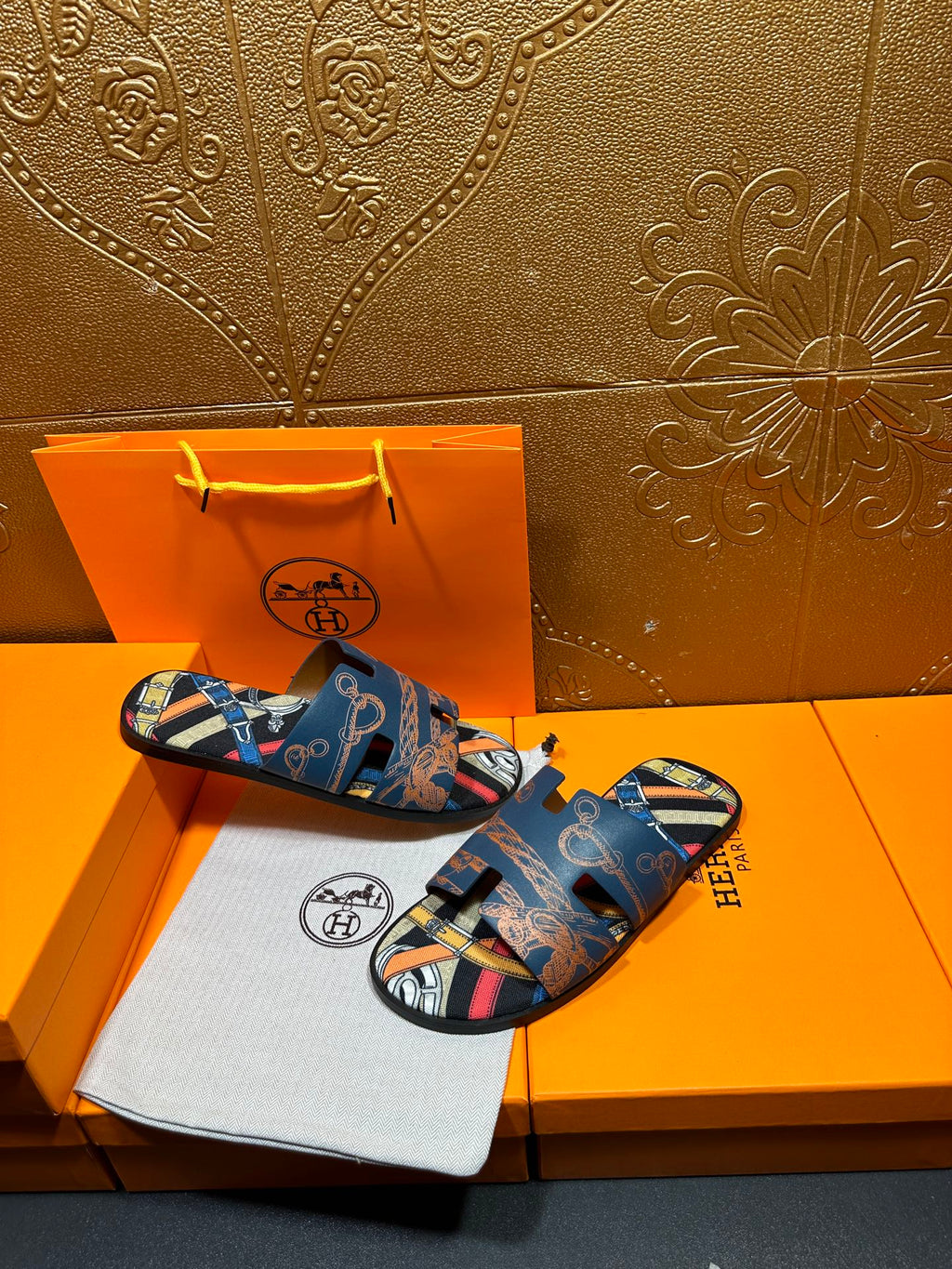 Blue Hermes logo slide sandals with patterned straps and open toe, side-by-side.