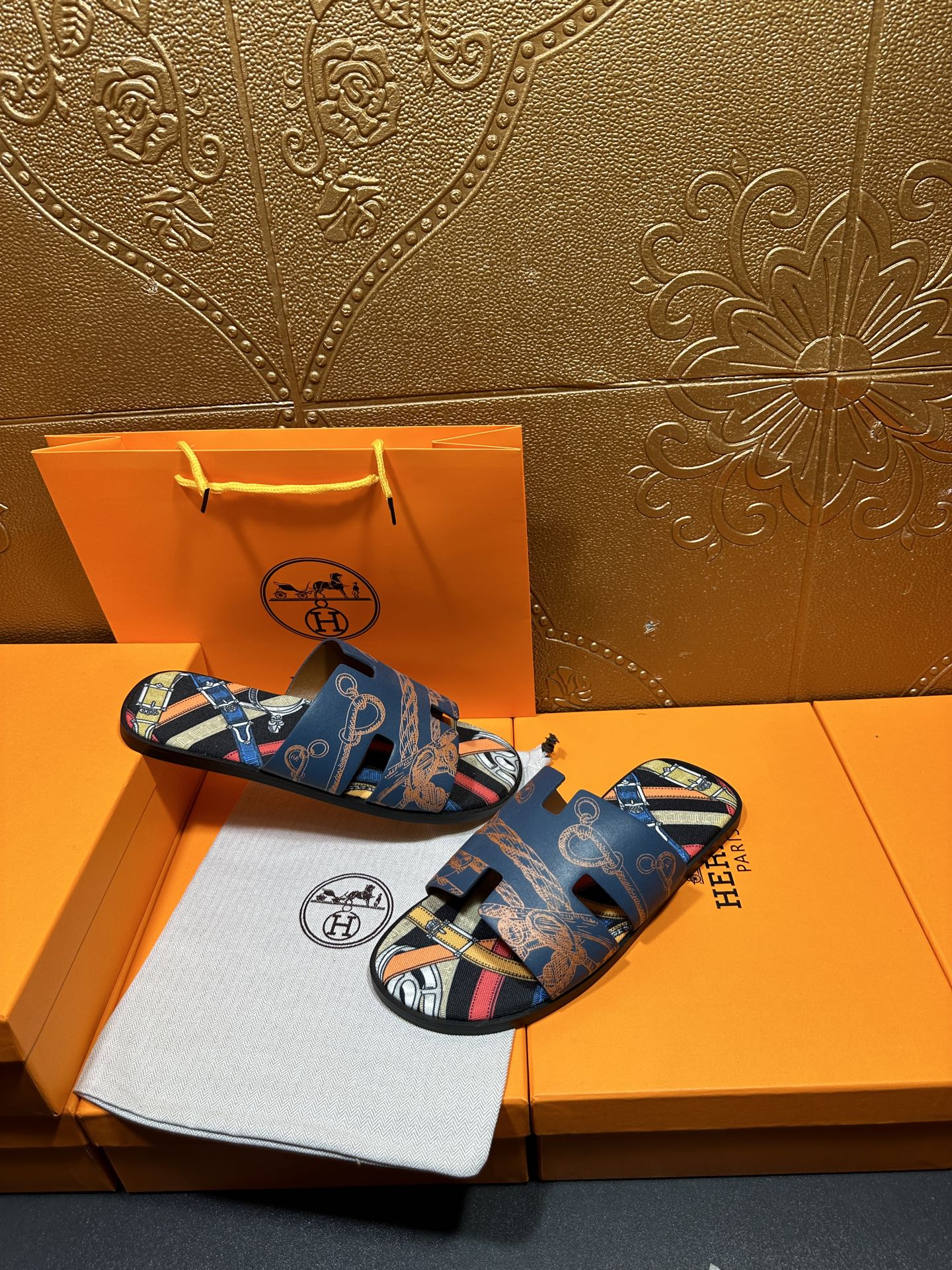 Blue Hermes logo slide sandals with patterned straps and open toe, side-by-side.