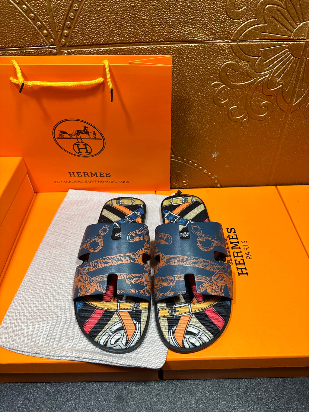 Blue Hermes logo slide sandals with patterned straps and open toe, front view.