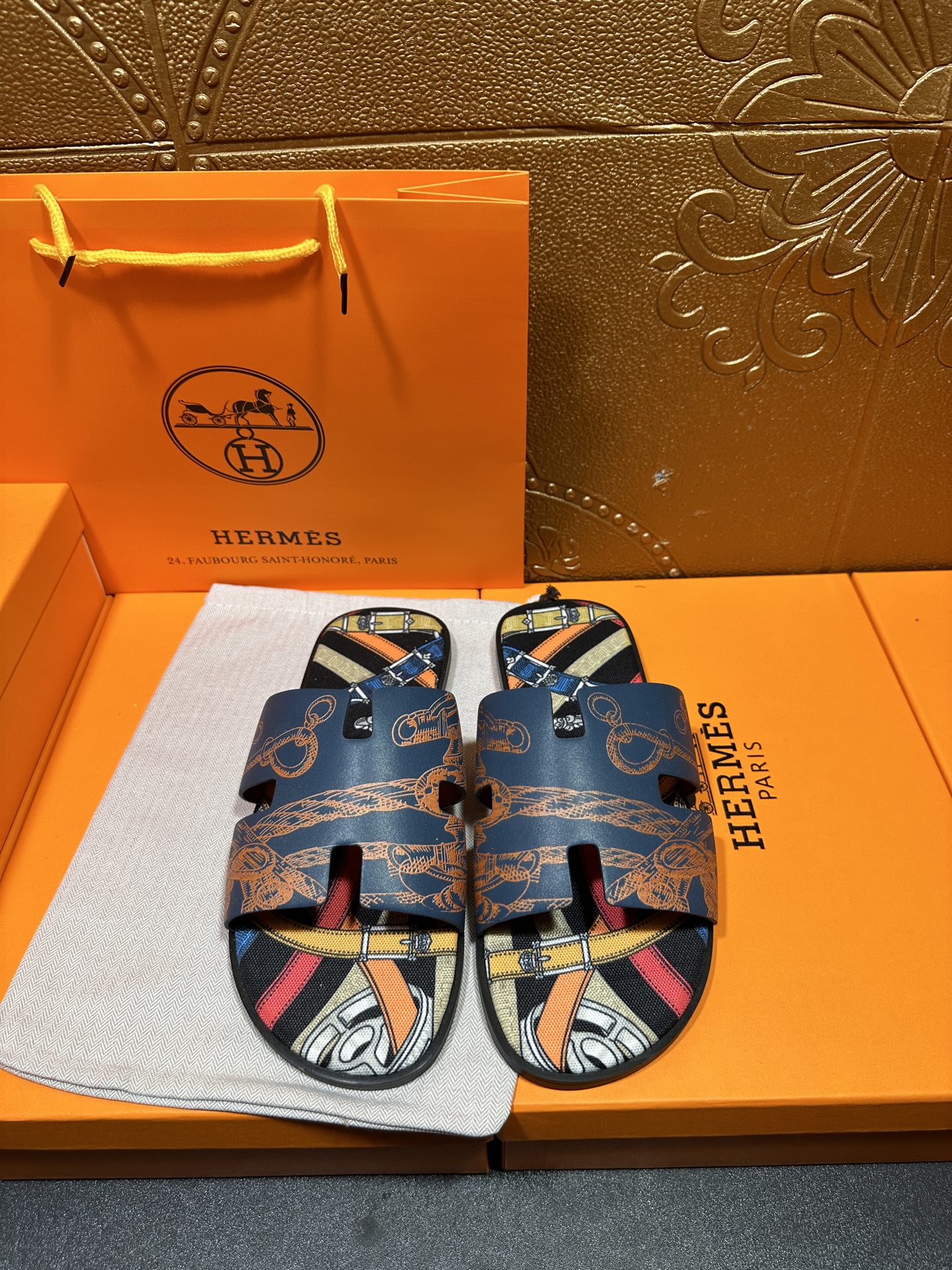 Blue Hermes logo slide sandals with patterned straps and open toe, front view.