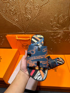 Blue Hermes logo slide sandals held in hand, open-toe design and patterned straps.