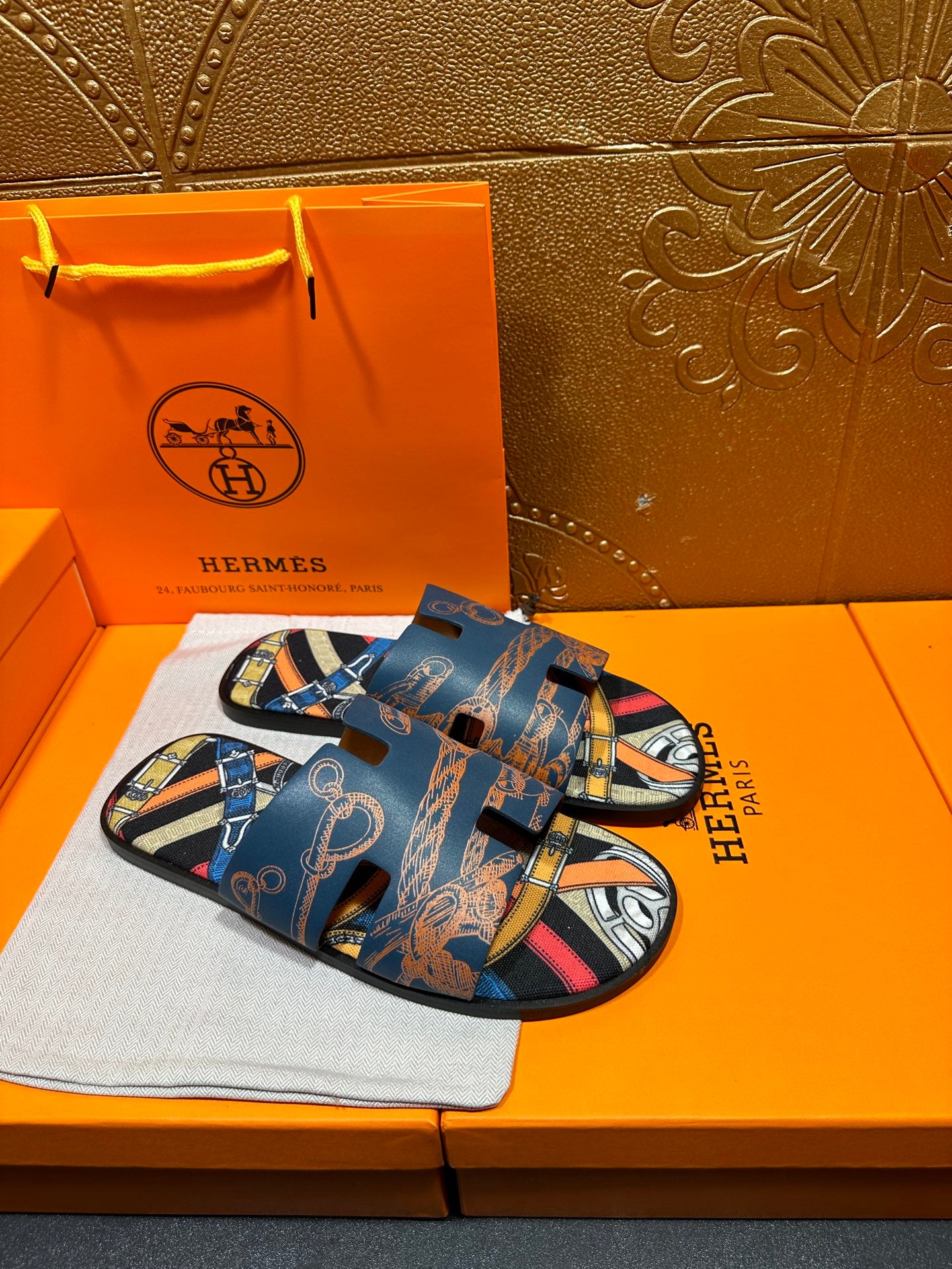 Blue Hermes logo slide sandals with patterned straps and open toe, side view.