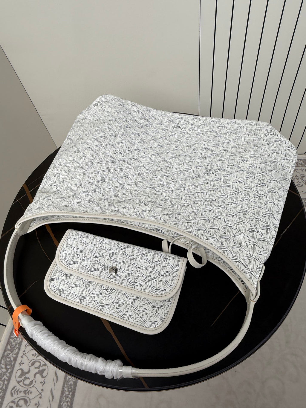 Goyard white hobo bag with matching pouch on top, monogram texture visible.