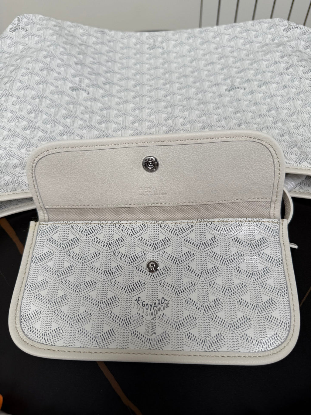 Goyard white mini pouch with monogram texture and leather flap with button.