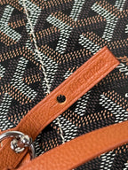 Goyard bag detail: tan leather strap with embossed text and metal snap hardware