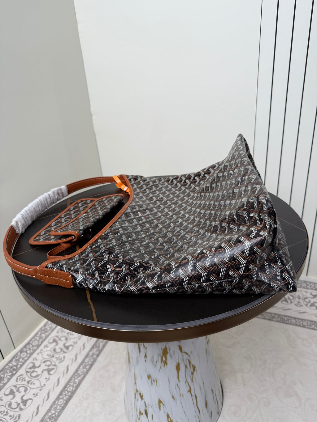 Goyard hobo bag with dark monogram pattern, orange handle accents, and braided top