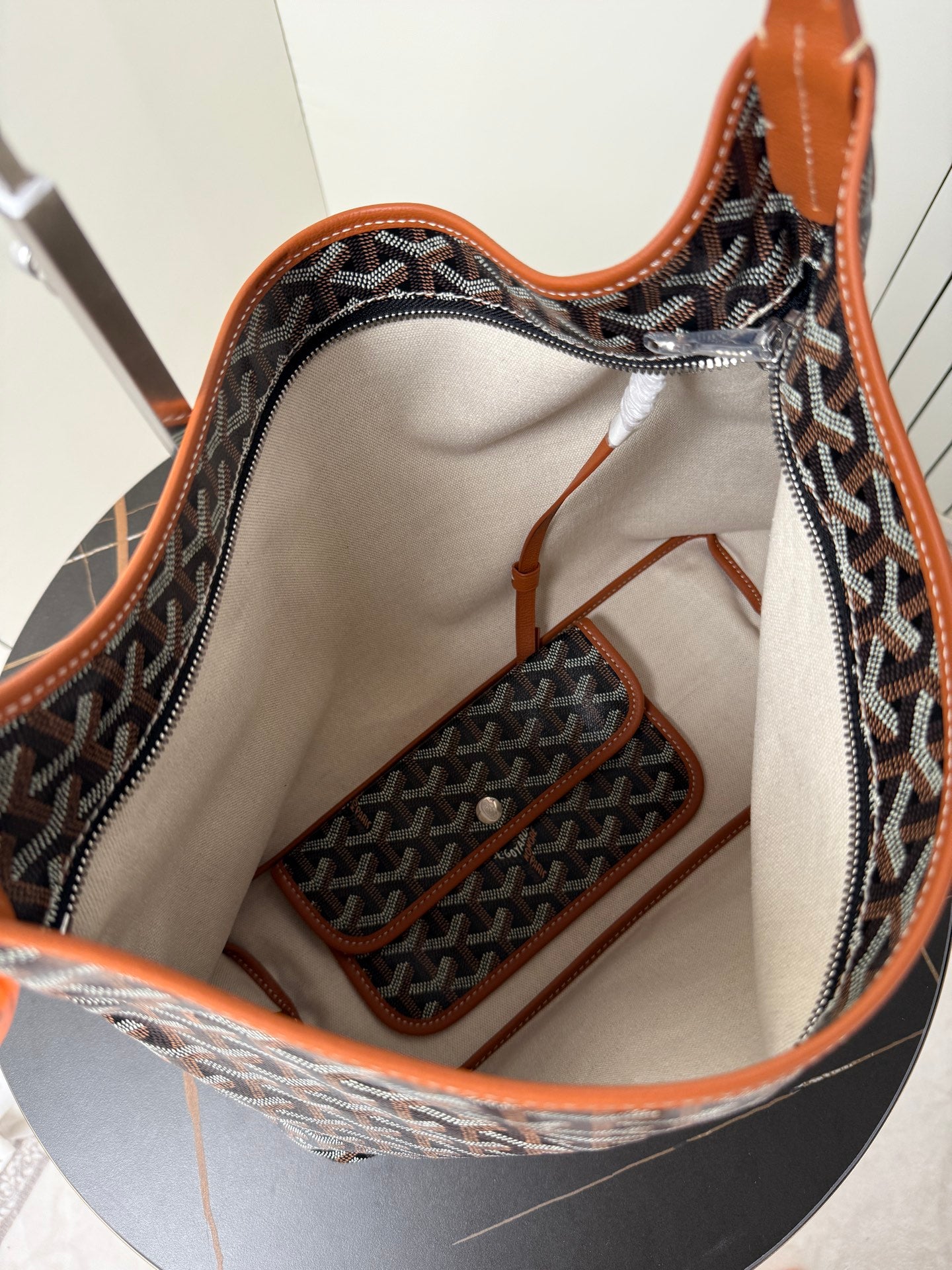 Goyard hobo bag interior view with beige lining and orange-trimmed pockets