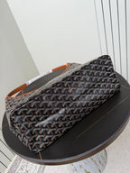 Goyard duffle-style bag with dark monogram pattern and orange-trimmed strap