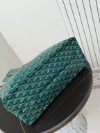Goyard teal bag with zip top and patterned Goyardine weave, angled side view.