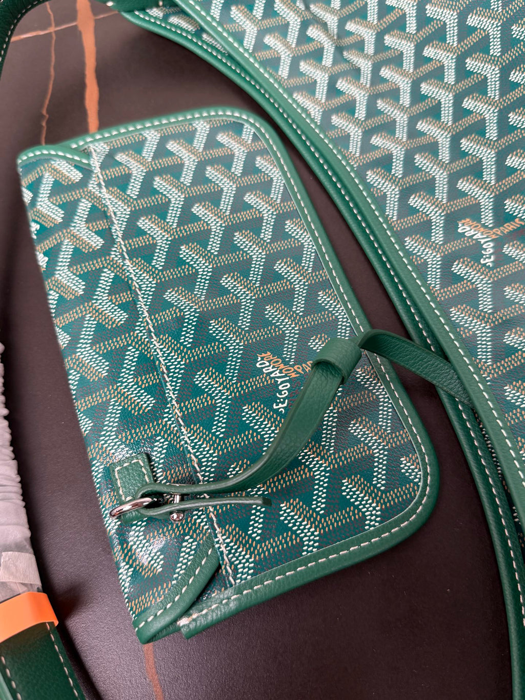 Goyard teal small pouch with snap button and patterned Goyardine weave, close-up.