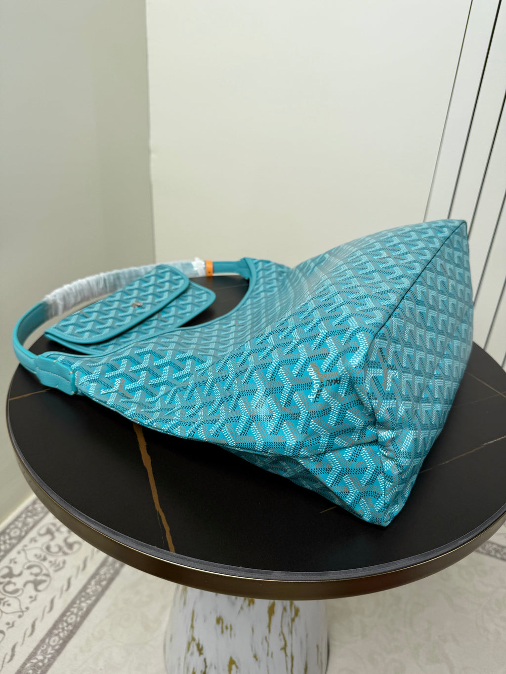 Goyard teal monogram hobo bag laid on side with handles and open top