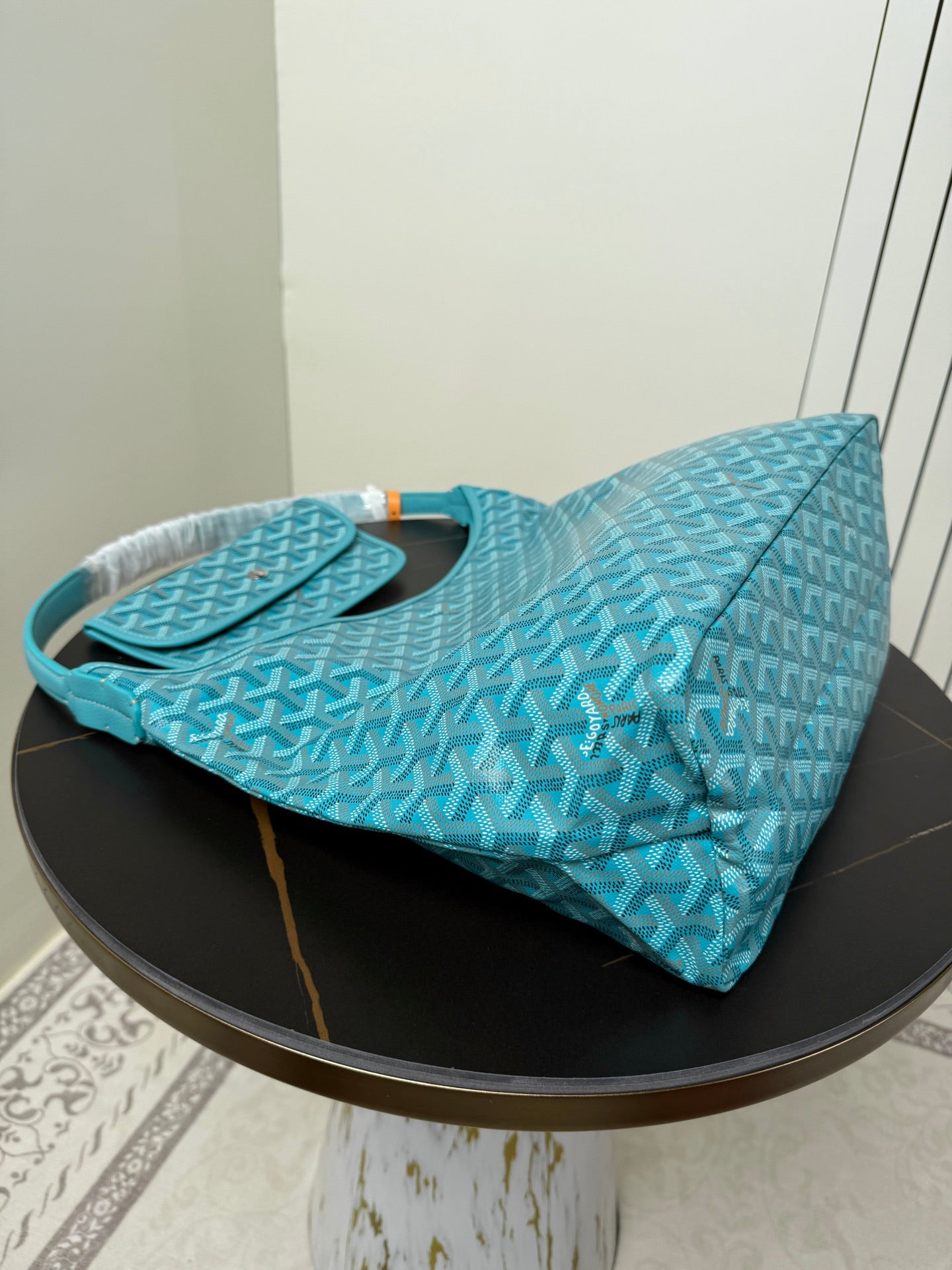 Goyard teal monogram hobo bag laid on side with handles and open top