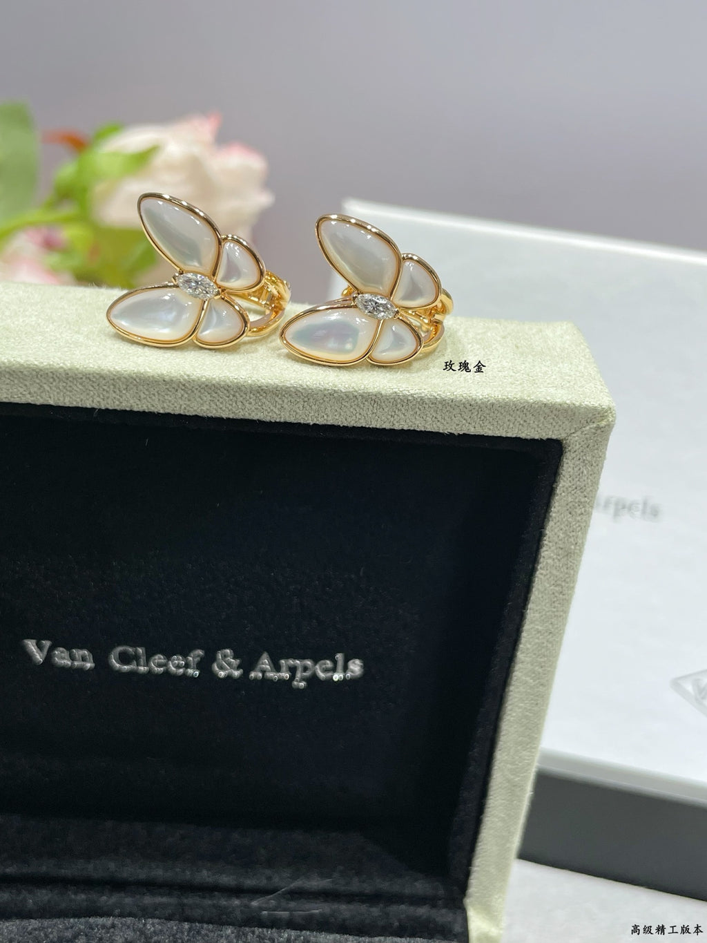 Gold-tone butterfly stud earrings with white mother-of-pearl petals on display box